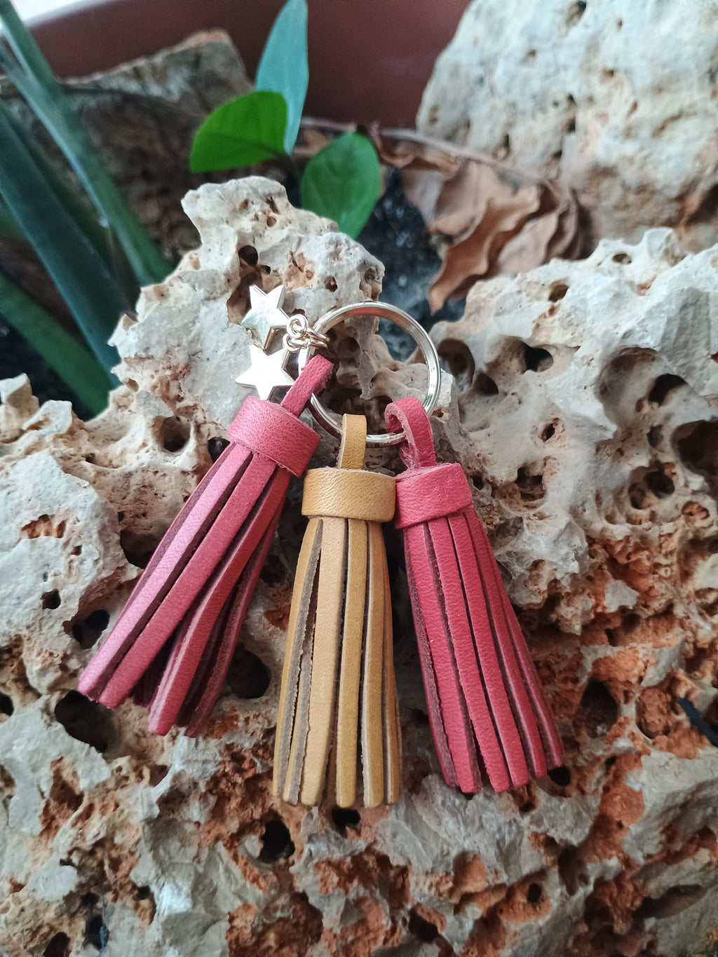 Llavero de piel artesanal con flecos en rojo, amarillo y frambuesa sobre piedra natural