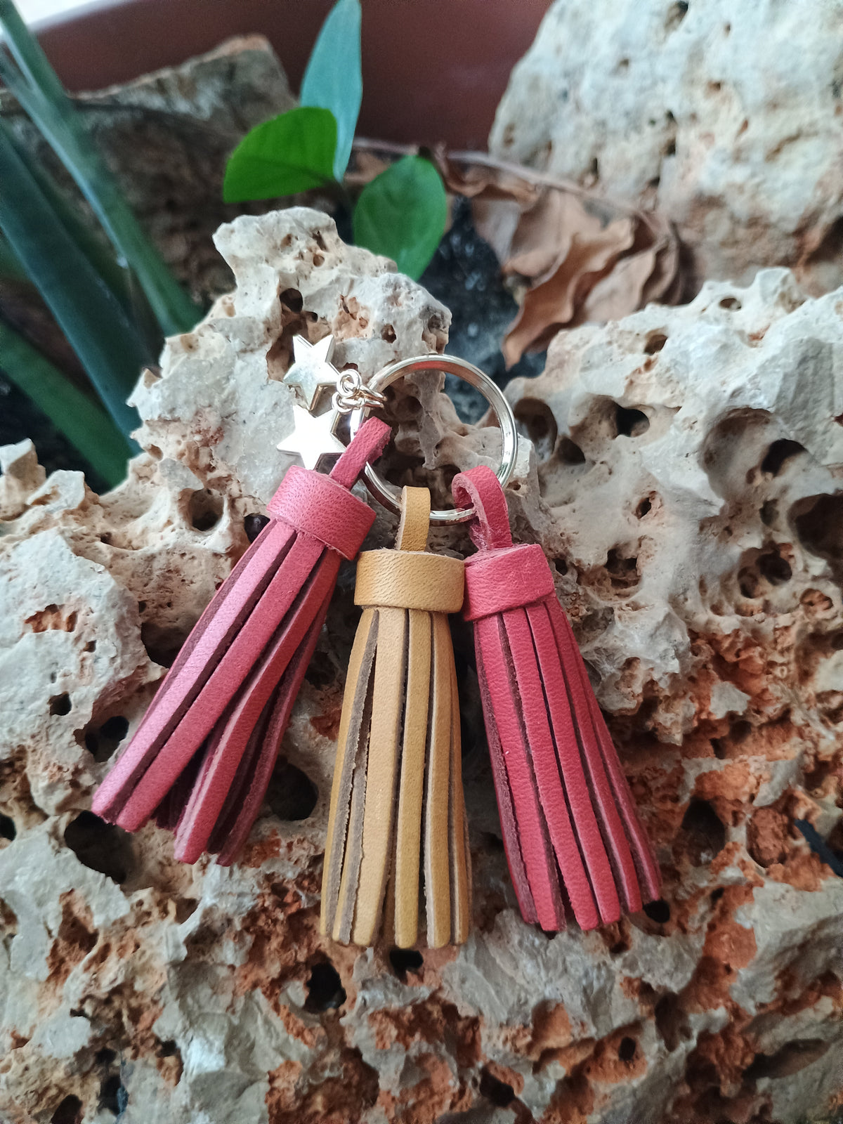Llavero de piel artesanal con flecos en rojo, amarillo y frambuesa sobre piedra natural