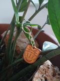 Llavero de piel personalizado con grabado láser escudo colgado en planta